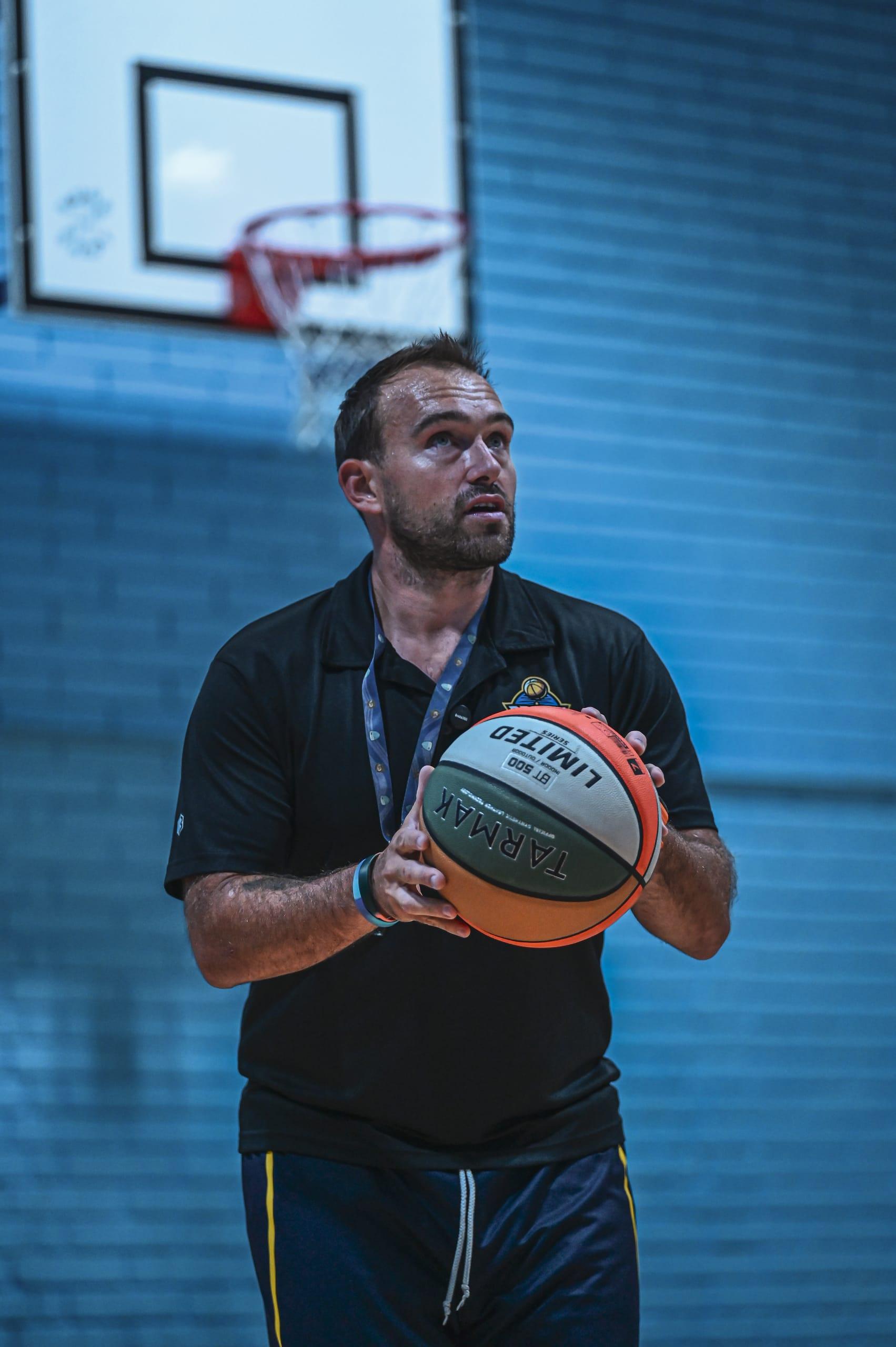 Coach Luca Dronyk holding a basketball on court